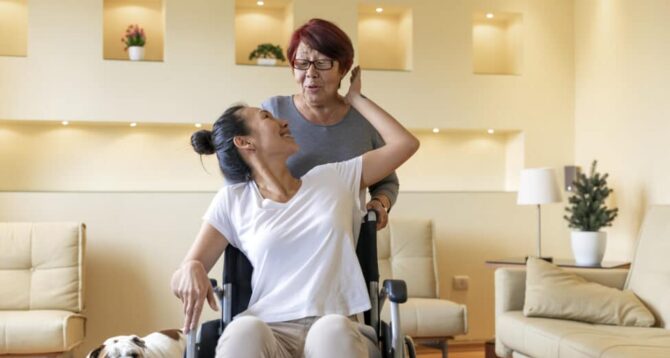 Mature Woman is Happy to Have a Caregiver by her Side. Asian Woman with Physical Disabilities is Glad to Receive Care by an Older Woman.