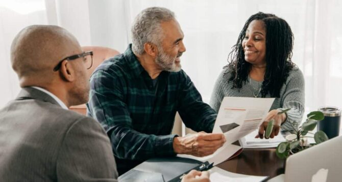 Three people sitting at a desk looking at reports associated with their Welcome to Medicare Visit.